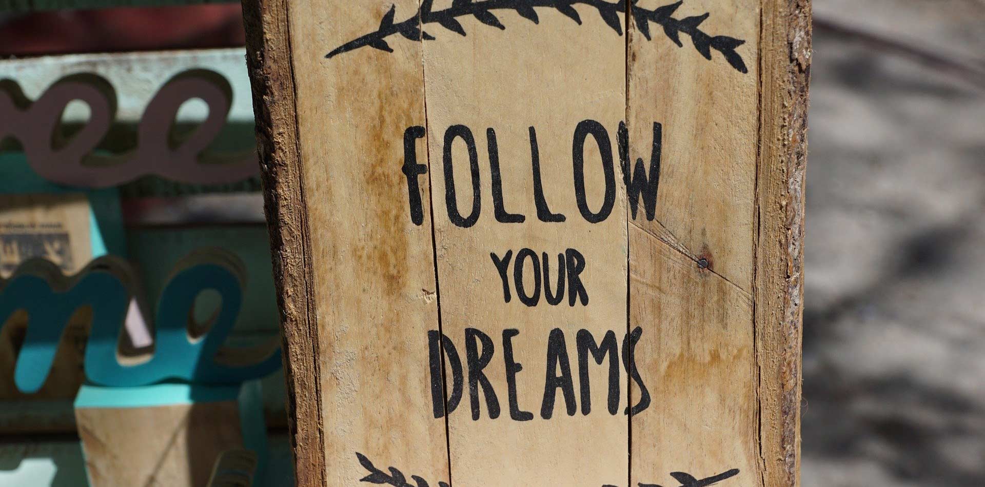 A sign carved into wood saying "follow your dreams"