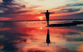 Person standing facing the sunrise