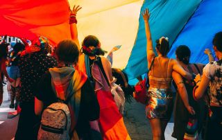 People of different sexuality walking under a rainbow flag