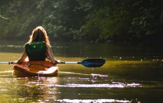 A woman canoeing on a calm river