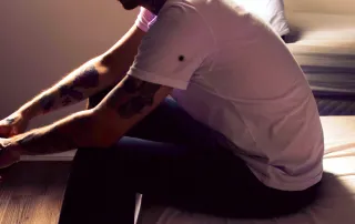 sad man sitting on bed edge