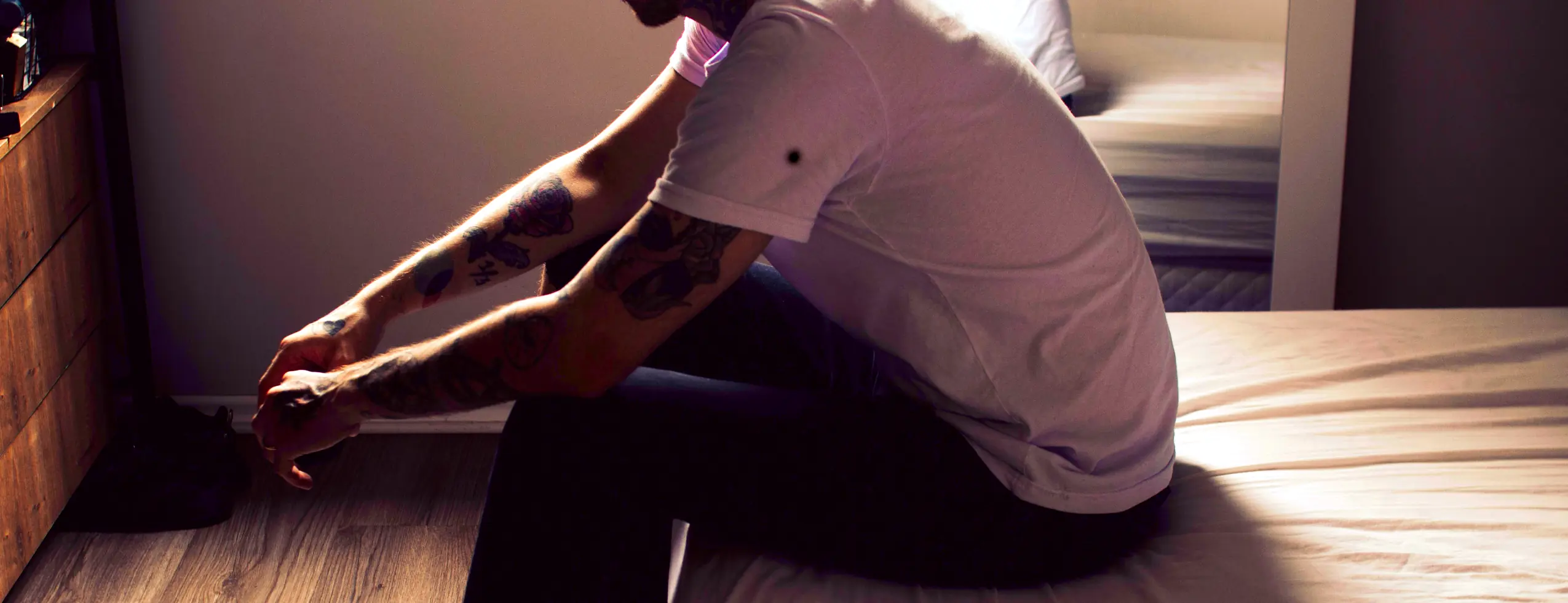 sad man sitting on bed edge