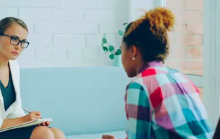 Therapist listening to client in a calm consulting room during a session.